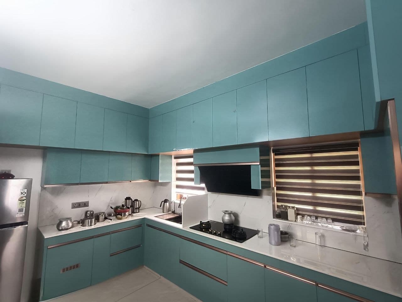 Finished kitchen with teal cabinetry, marble backsplash and brass trim